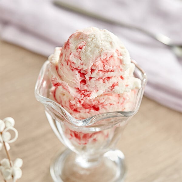 A glass cup with a scoop of Oringer strawberry variegate ice cream.