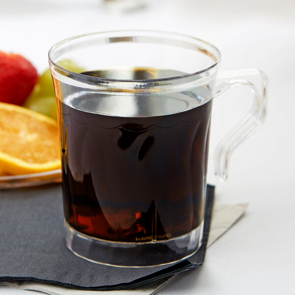 A Fineline clear plastic coffee mug filled with a liquid and a slice of orange.