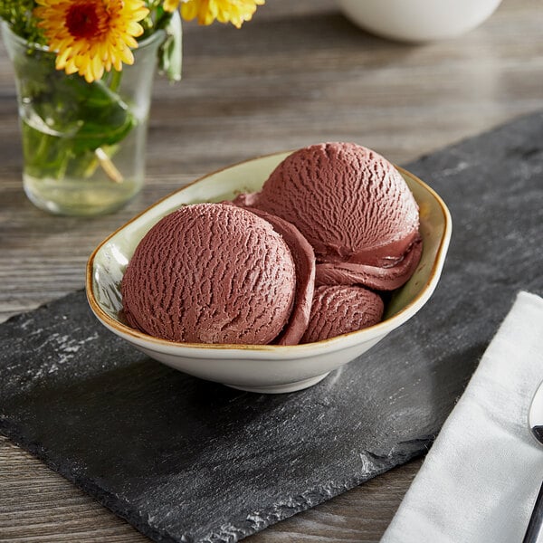 A bowl of Oringer black cherry ice cream with chocolate sauce on top.