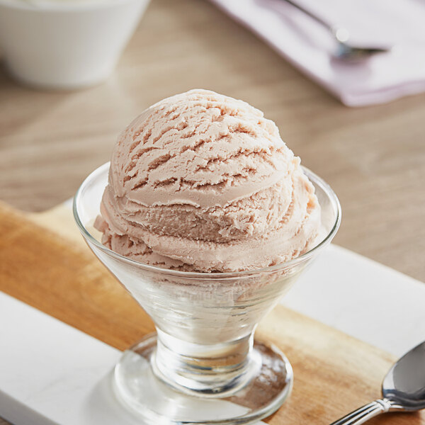 A bowl of Oringer black raspberry ice cream with a spoon on a wooden surface.