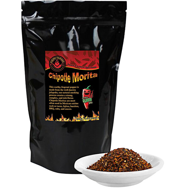 A black bag of Fiery Farms Chipotle Morita Pepper Flakes with a bowl of the pepper flakes.
