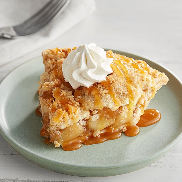 A slice of pie with Oringer caramel dessert topping on a plate with whipped cream.
