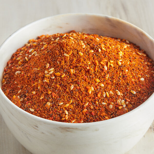 A bowl of red and black spices, including McCormick Culinary Salad Supreme Seasoning.