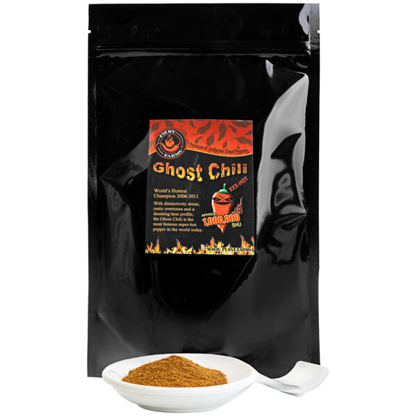 A black bag of Fiery Farms Red Ghost Pepper Powder with a label on it next to a white bowl of brown powder.