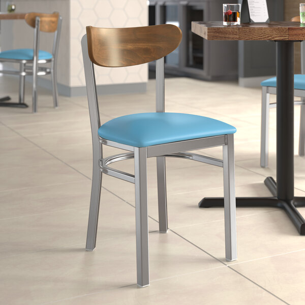 A Lancaster Table & Seating Boomerang chair with blue vinyl seat at a table in a restaurant.