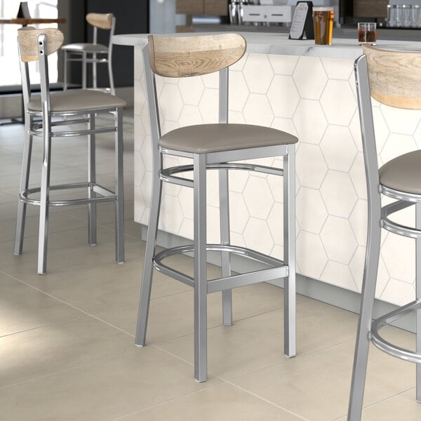 Lancaster Table & Seating bar stools with a driftwood back and dark gray vinyl seats at a counter.