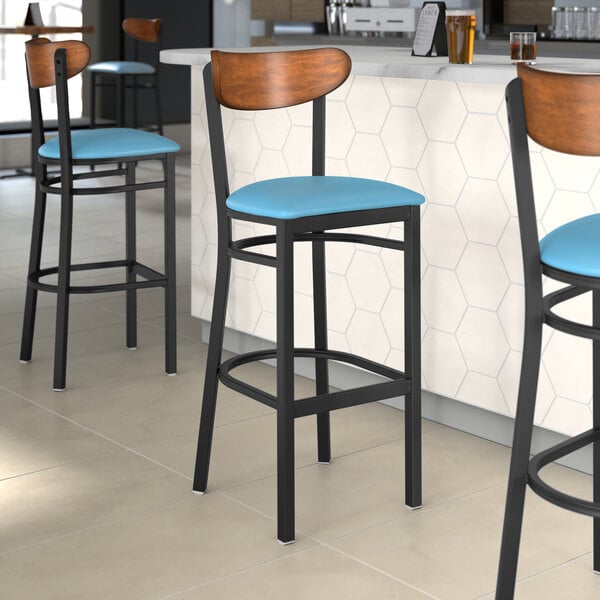 Three Lancaster Table & Seating bar stools with blue vinyl seats and antique walnut backs.