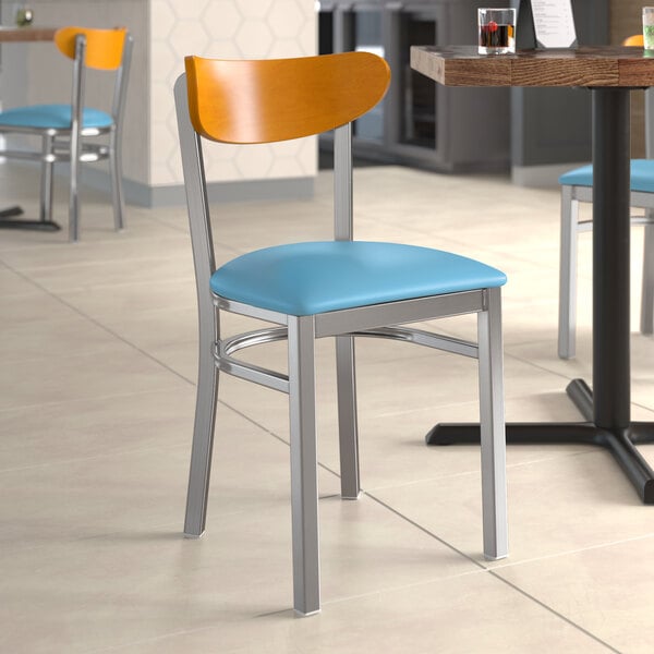 A Lancaster Table & Seating chair with a blue vinyl seat and cherry wood back on a table in a restaurant.