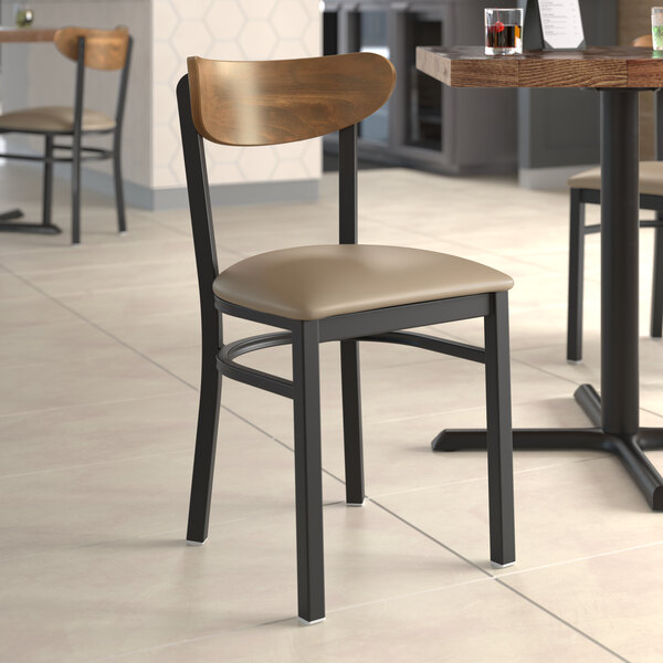 A Lancaster Table & Seating Boomerang Series chair with a wooden seat and back at a restaurant table.