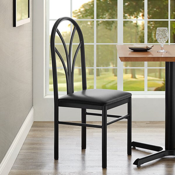 A Lancaster Table & Seating black vinyl chair next to a table.