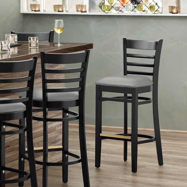 A Lancaster Table & Seating black wood bar stool with a light gray vinyl seat.