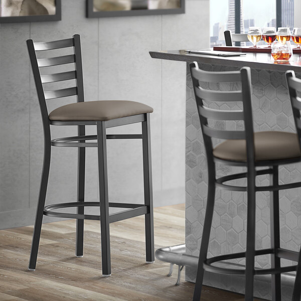 Lancaster Table & Seating Black Finish Ladder Back Bar Stool with 2 1/2" Taupe Vinyl Padded Seat