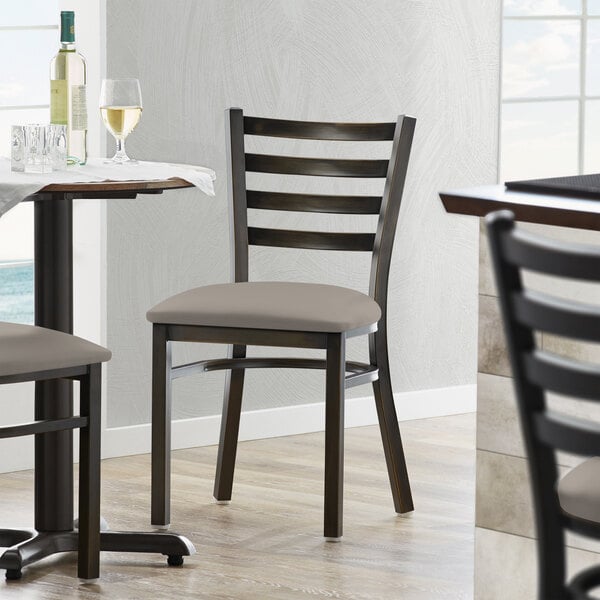 A Lancaster Table & Seating ladder back chair with a dark gray padded seat.