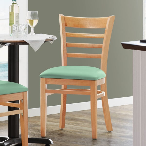 A Lancaster Table & Seating wooden chair with a seafoam green vinyl cushion.