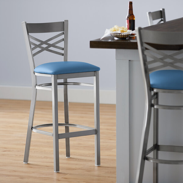 Lancaster Table & Seating Clear Coat Finish Cross Back Bar Stool with 2 1/2" Blue Vinyl Padded Seat