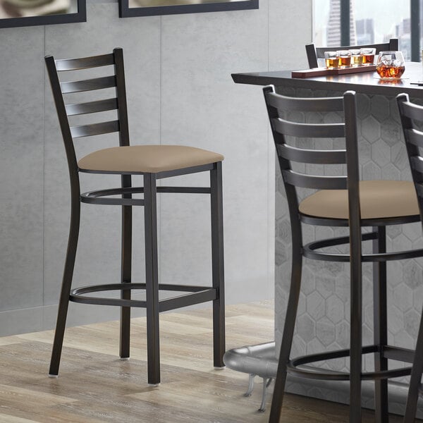 A Lancaster Table & Seating bar stool with a taupe vinyl padded seat.