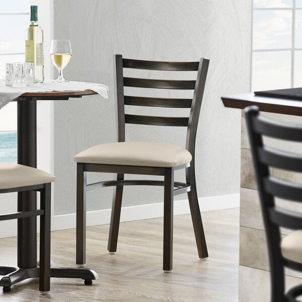A Lancaster Table & Seating distressed copper finish ladder back chair with a light gray padded seat.