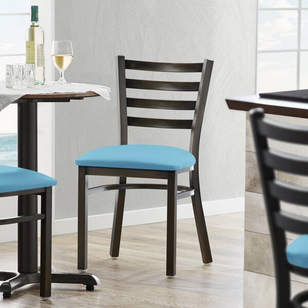 A Lancaster Table & Seating Ladder Back Chair with blue vinyl padding on the seat.