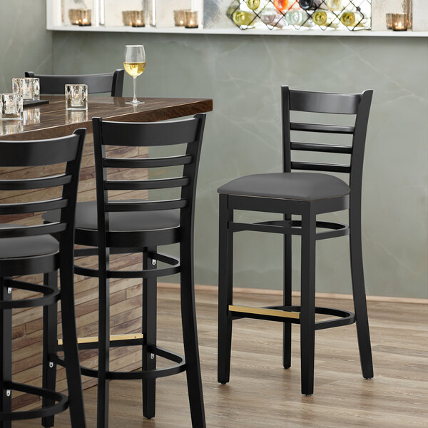 A Lancaster Table & Seating black wood bar stool with a dark gray seat.