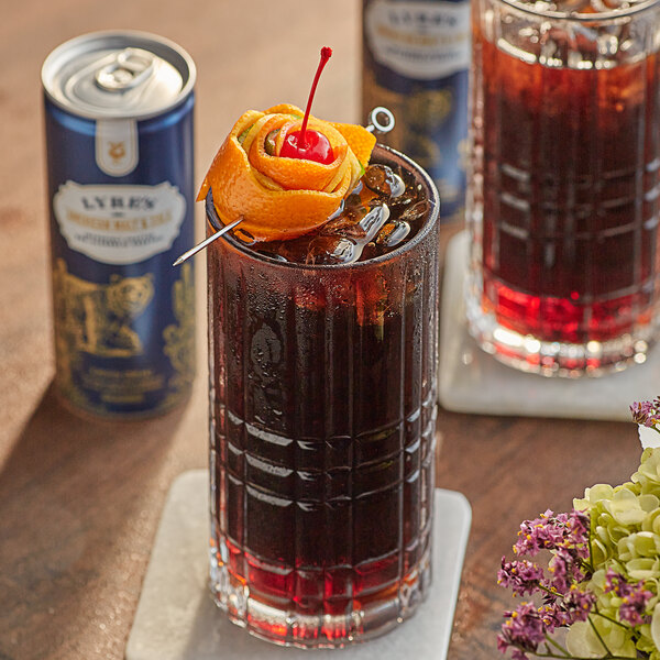 A Lyre's American Malt and Cola non-alcoholic mocktail in a glass with a cherry on top.