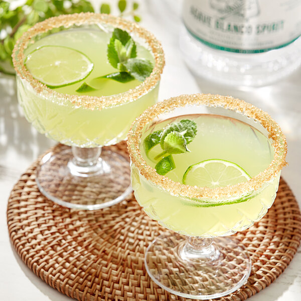 A table with two glasses of Lyre's Agave Blanco with limes and mint.