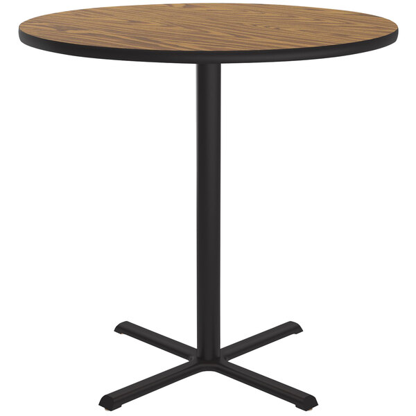 A Correll round table with a medium oak thermal-fused laminate top and black bar height base.