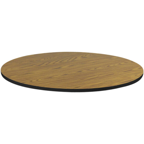 A close-up of a Correll round medium oak thermal-fused laminate table top with a black edge.