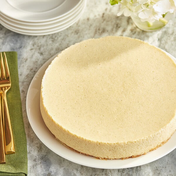 A round white cake on a white plate with a slice cut out.