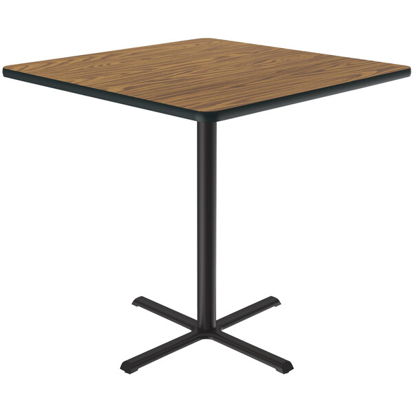 A Correll square table with a medium oak thermal-fused laminate top and black metal base.