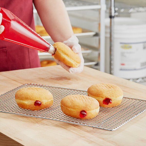 A person using Rich's Allen Raspberry Flavored Filling to put jelly in doughnuts.