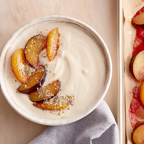 A bowl of Pequea Valley Farm maple yogurt with sliced plums and nuts.