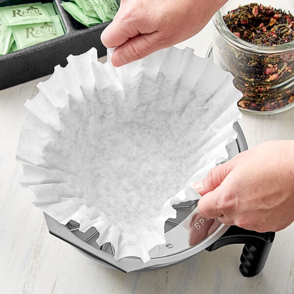 A person's hands using a Choice paper tea filter to make tea.