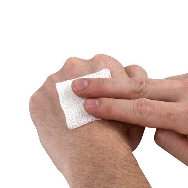 A person using a Medi-First sterile gauze pad on their wrist.