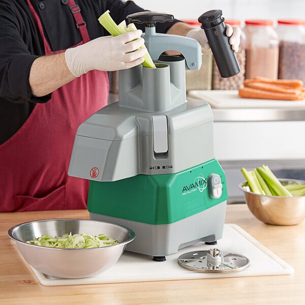 A person using the AvaMix commercial food processor to slice celery.