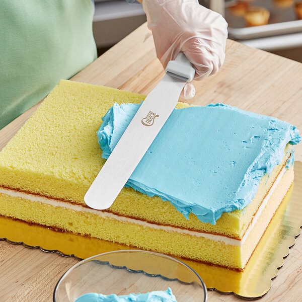 A person using a Choice straight blade spatula to frost a cake.