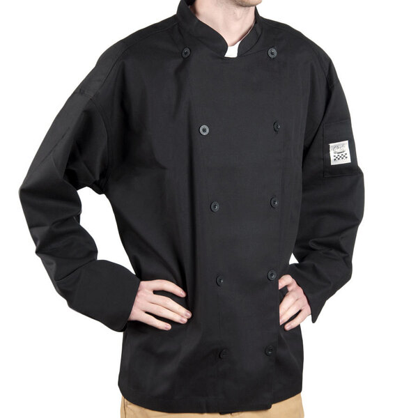 A man wearing a black Chef Revival chef coat in a professional kitchen.