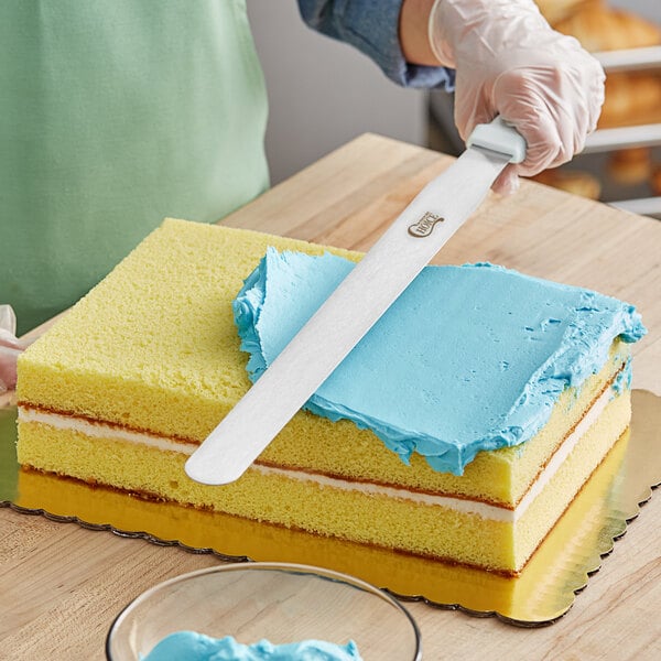 A person using a Choice baking spatula to cut a cake.