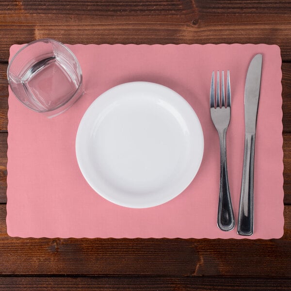 A white plate with a fork and knife on a Hoffmaster Dusty Rose Pink paper placemat.