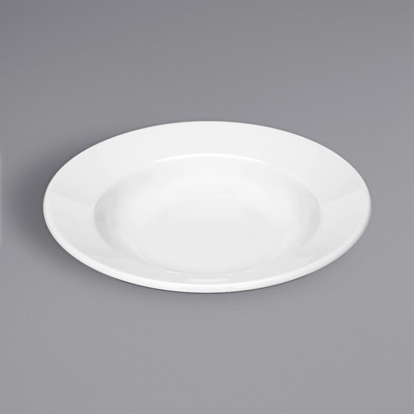 A Bauscher bright white porcelain coupe plate with a rim on a gray surface.