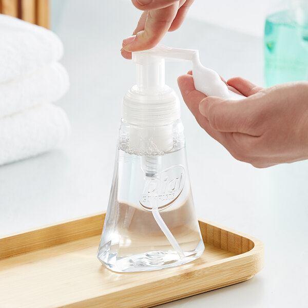 A hand using a Dial foaming hand soap pump to dispense white soap.