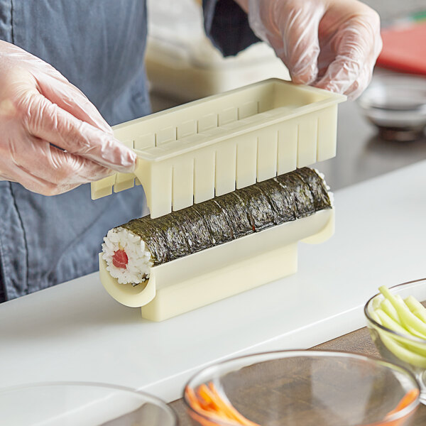 A person using the Emperor's Select sushi mold to make a sushi roll.