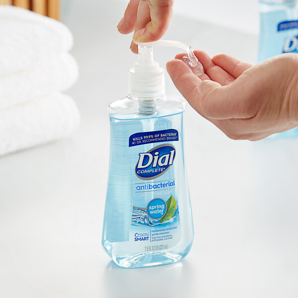 A hand using a pump of Dial Spring Water Antibacterial Liquid Hand Soap.