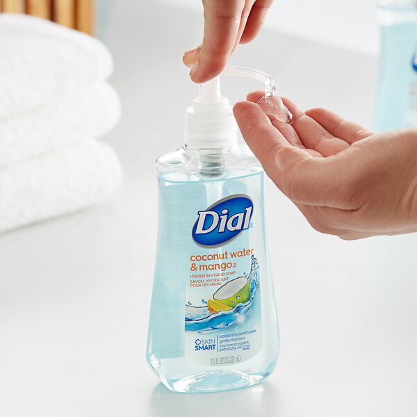 A hand using a pump to pour Dial Coconut Water Mango liquid hand soap from a plastic bottle.