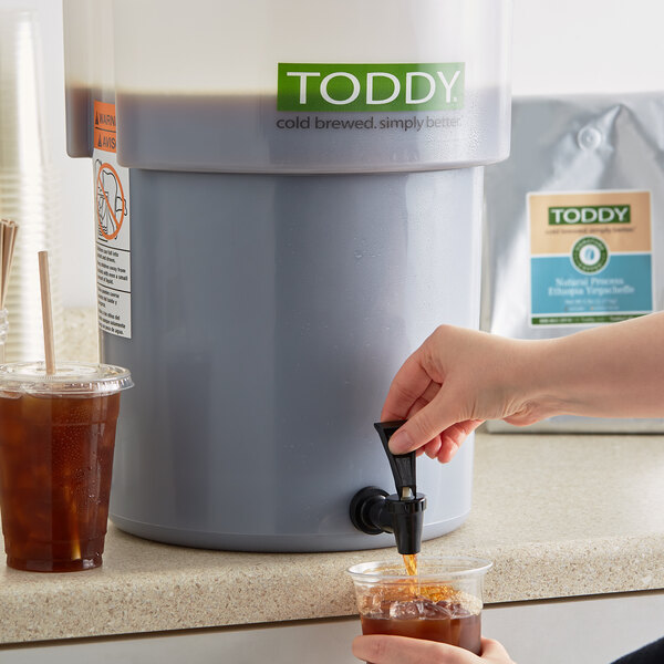 A person pouring Toddy Ethiopia Yirgacheffe cold brew into a plastic cup.