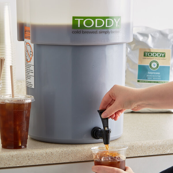 A person pouring Toddy cold brew coffee into a glass.