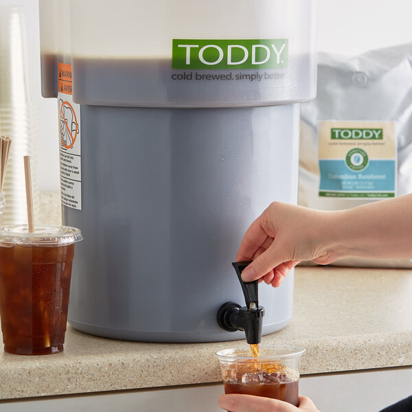 A person pouring Toddy Colombian Cold Brew Coffee into a glass.