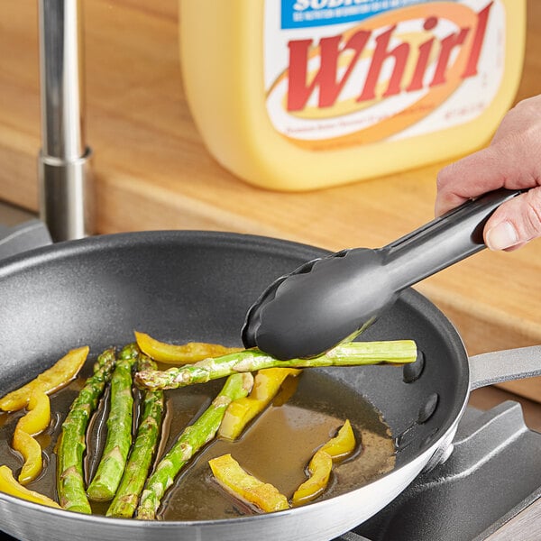 A hand cooking asparagus in a pan using Whirl Butter Flavored Oil