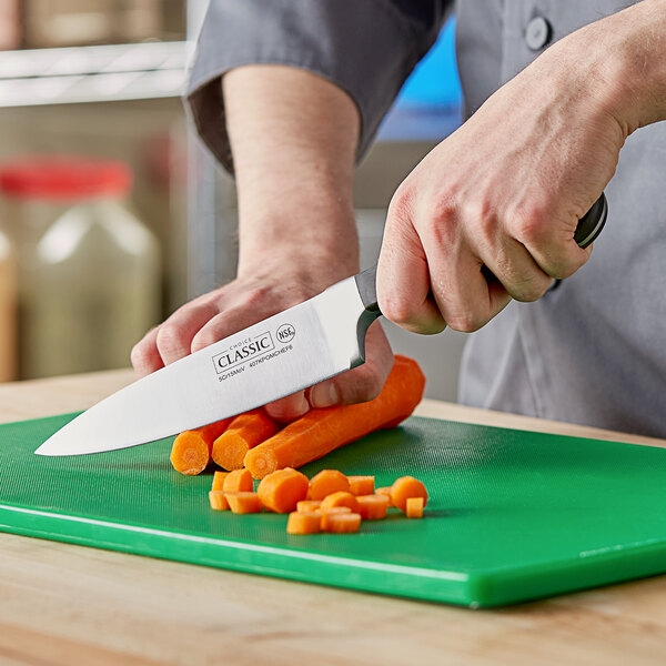 A person using a Choice Classic Chef Knife to slice carrots on a cutting board.