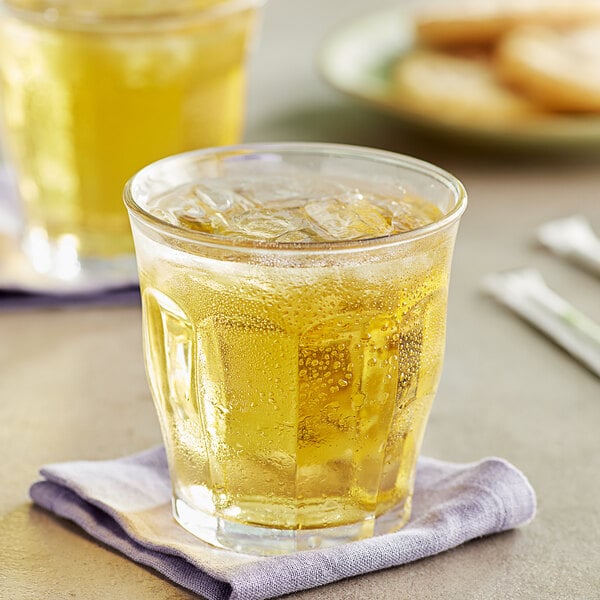 A glass of Old Orchard White Grape fruit juice concentrate with ice and a plate of cookies.
