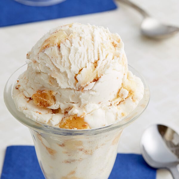 A glass cup with a scoop of Baked Cheesecake Pieces ice cream.